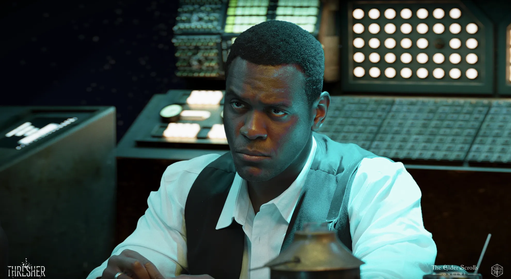 Serious man with short hair wearing a white shirt and black vest sitting at a desk with complex electronic panels and circular lights behind him.