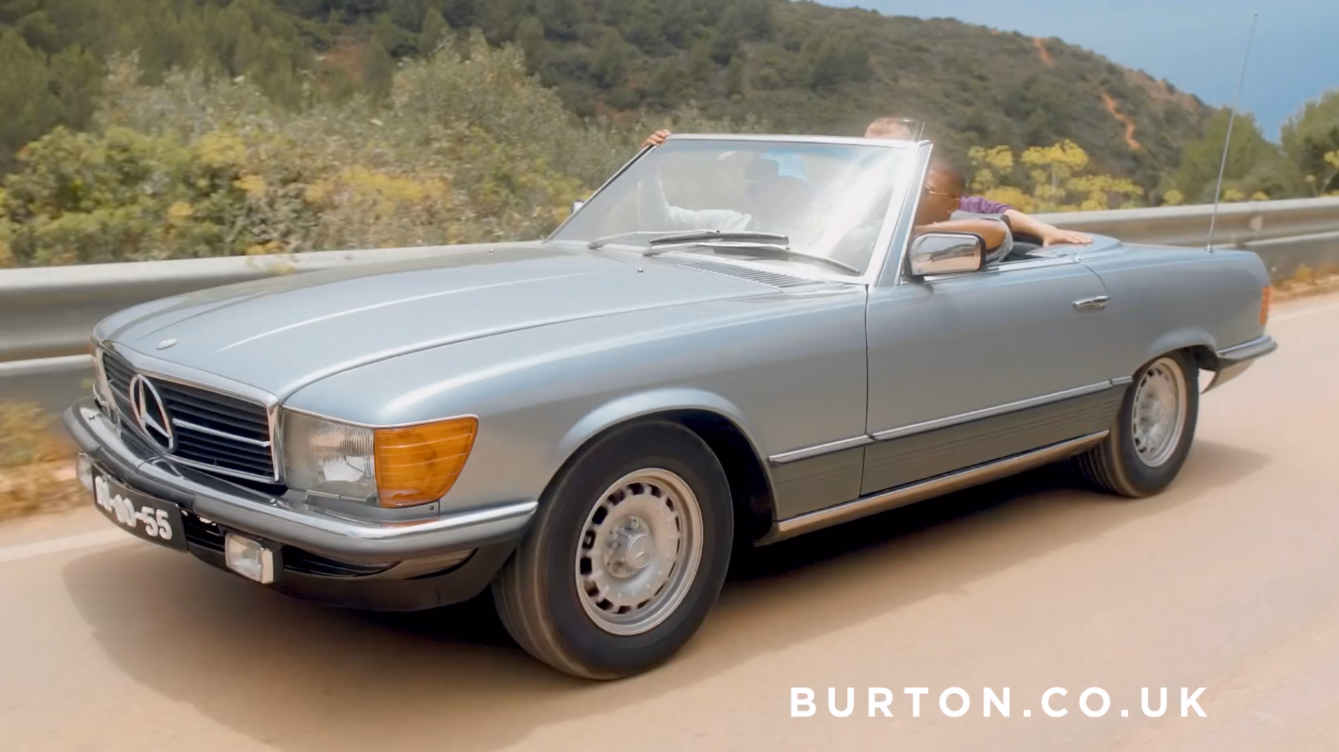 Classic silver Mercedes convertible driving along a coastal road, from a Burton.co.uk campaign