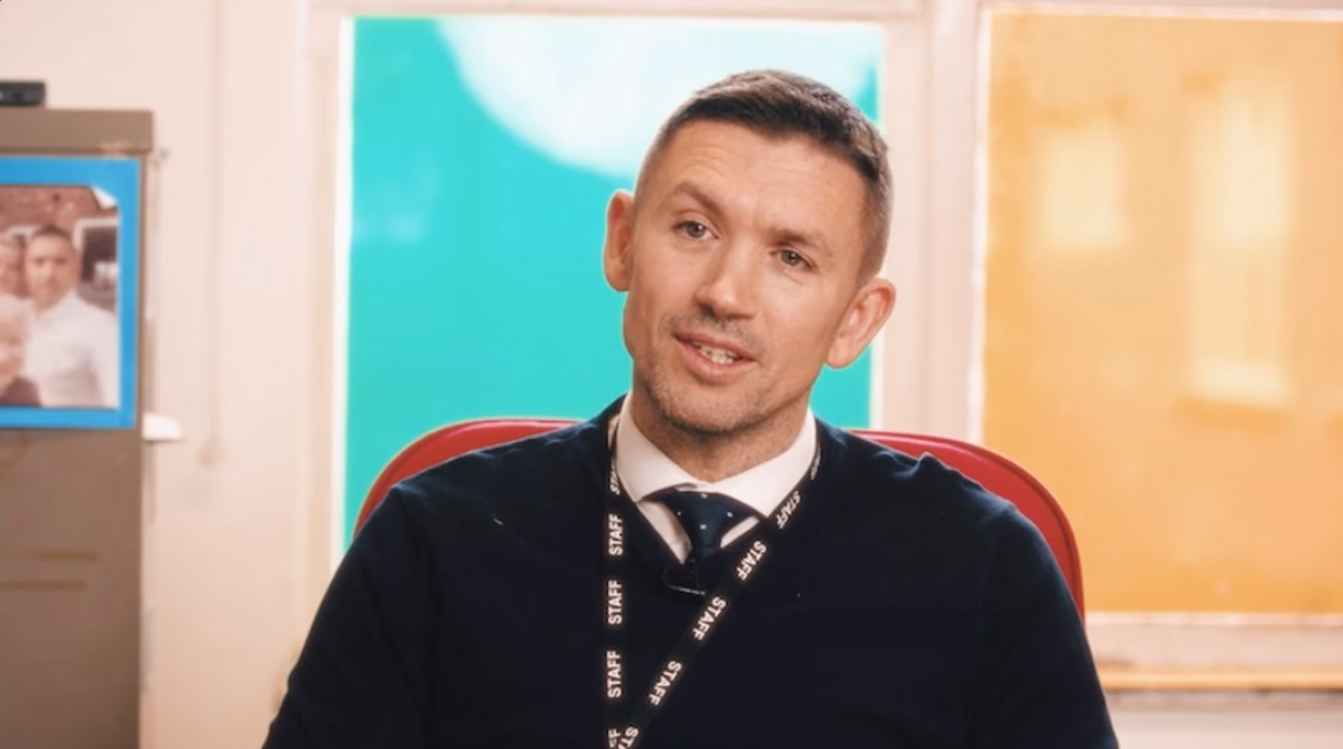 Man wearing a staff lanyard being interviewed in an office breakout space, from a TRAC production