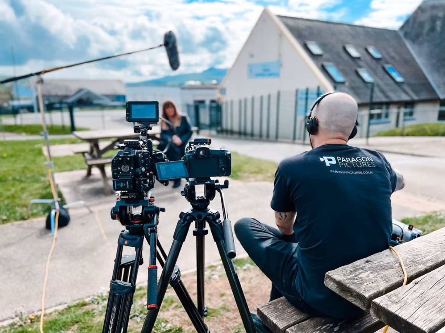 Behind-the-scenes shot of the Paragon Pictures crew filming an interview outdoors with camera and boom mic