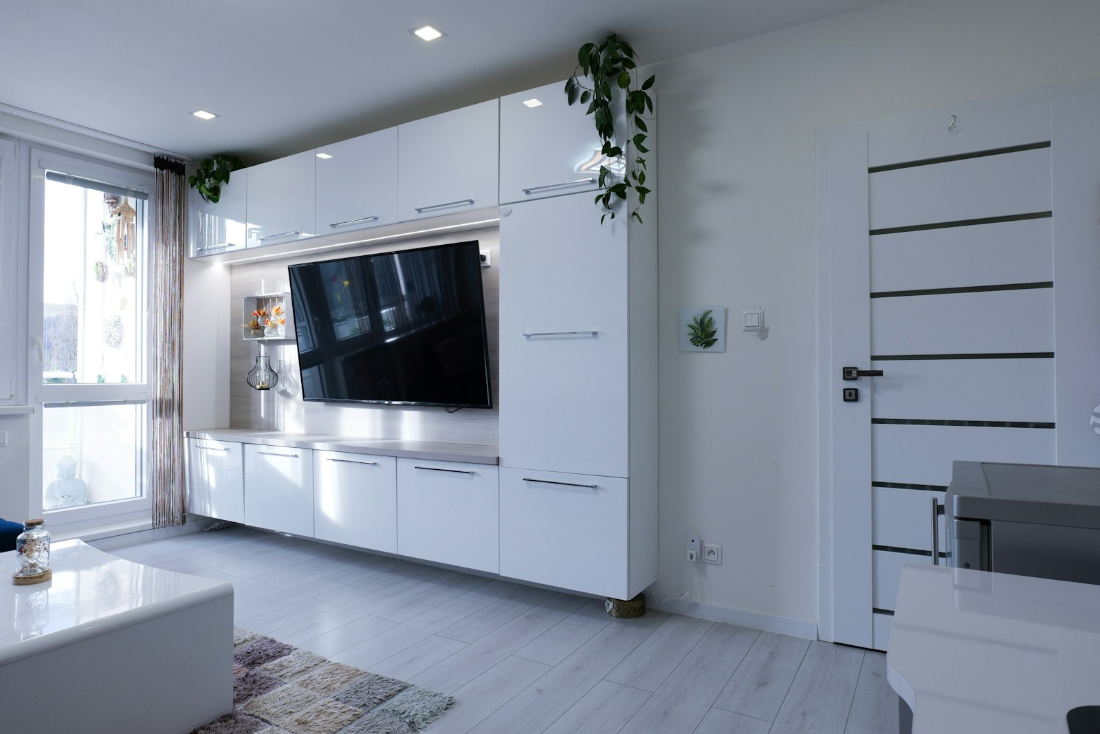 A tidy, freshly cleaned modern living room with white cabinetry and natural light
