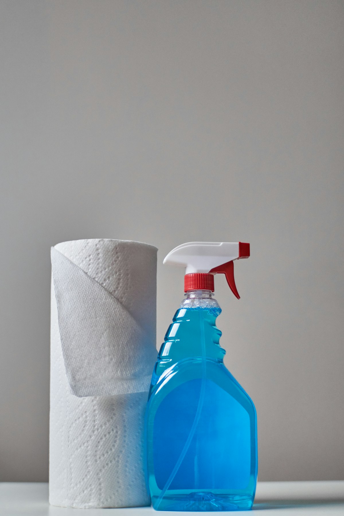 A clear spray bottle of cleaning solution, ready for wiping down glass surfaces