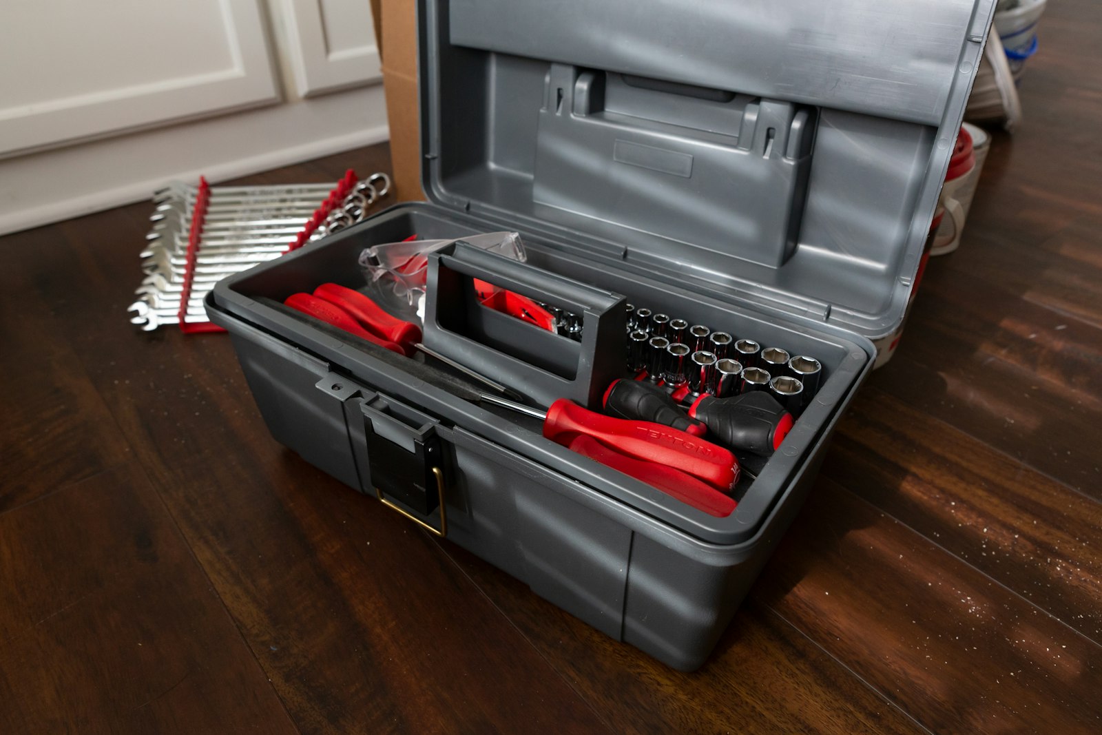 An open handyman toolkit filled with hand tools on a wooden table
