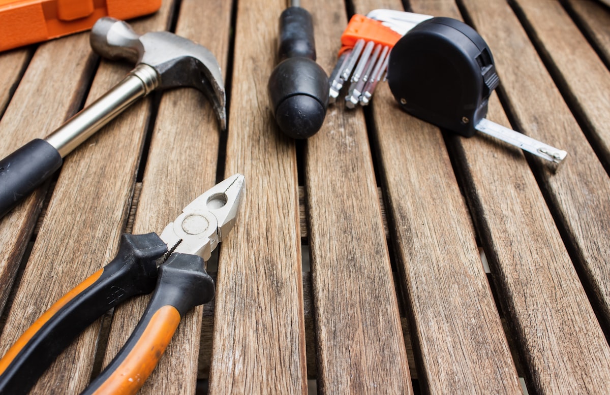 An assortment of carpentry and repair tools laid out on a wooden surface