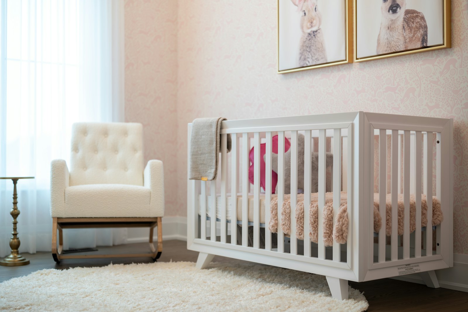 A cosy nursery with a white cot and rocking chair beside a bright window