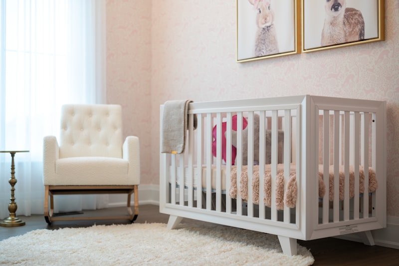 A cosy nursery with a white cot and rocking chair beside a bright window