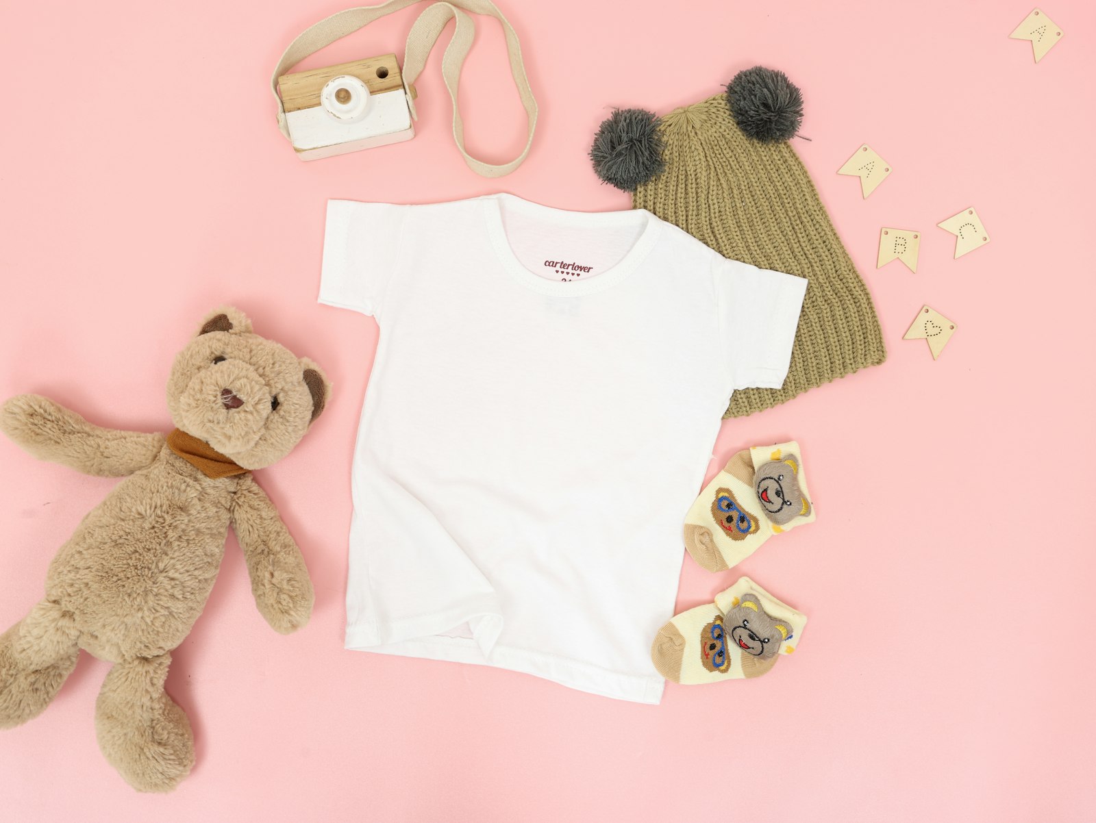 Freshly washed baby clothes laid out with a knitted hat and plush toys