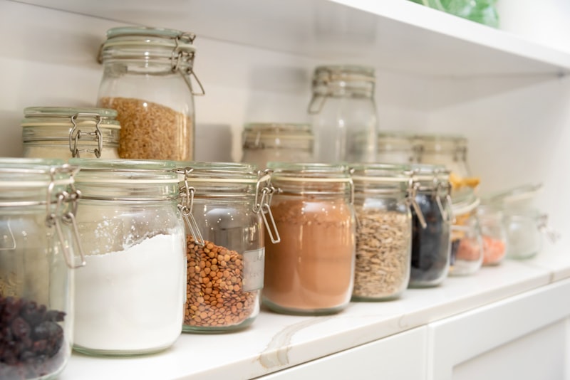 Airtight glass jars of dry food neatly arranged on a bright white kitchen shelf