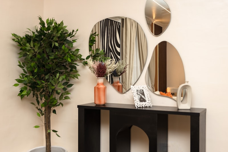 A bright, modern entryway with a console table, round mirrors and a potted plant