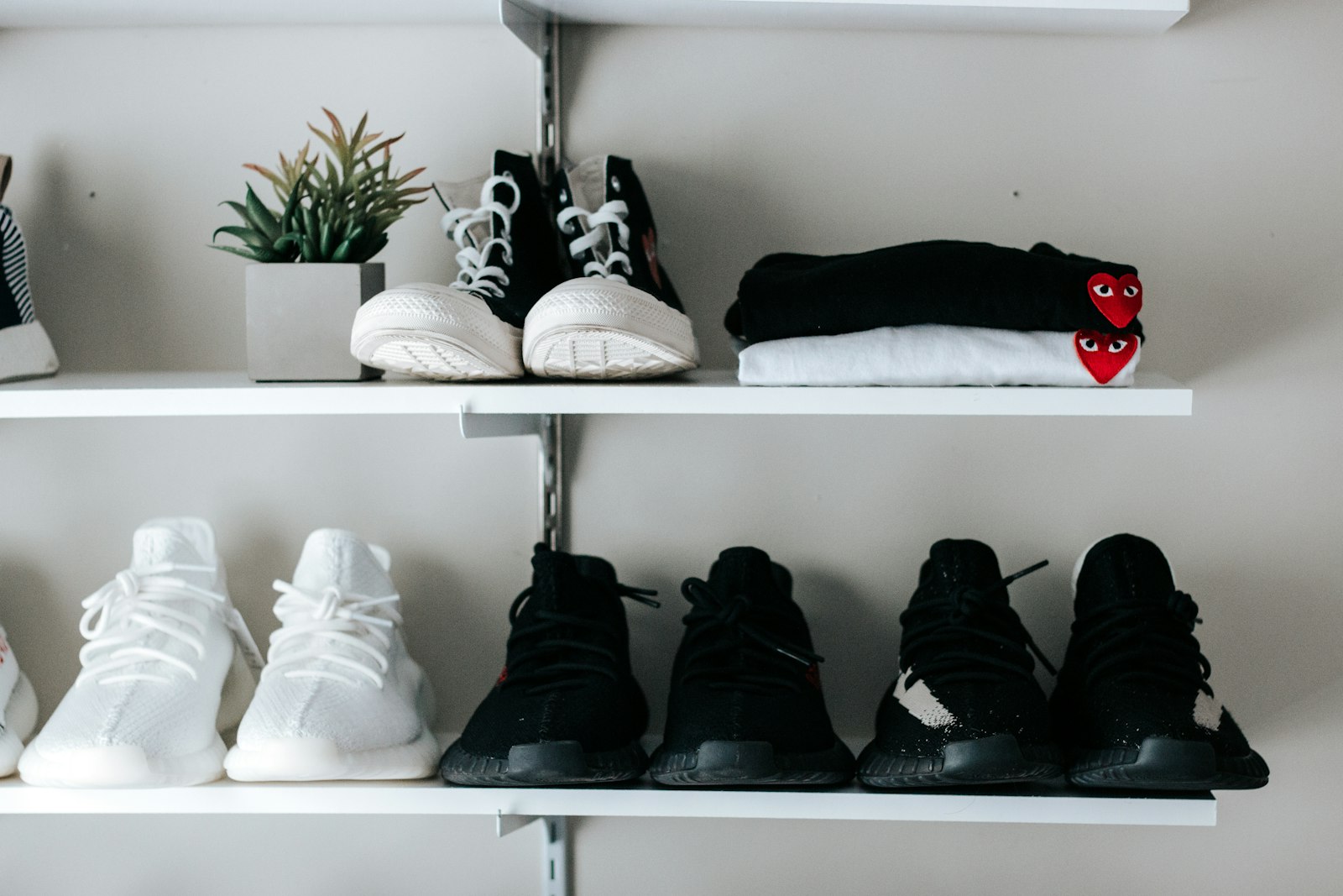 Trainers and shoes arranged neatly on white shelves by a doorway