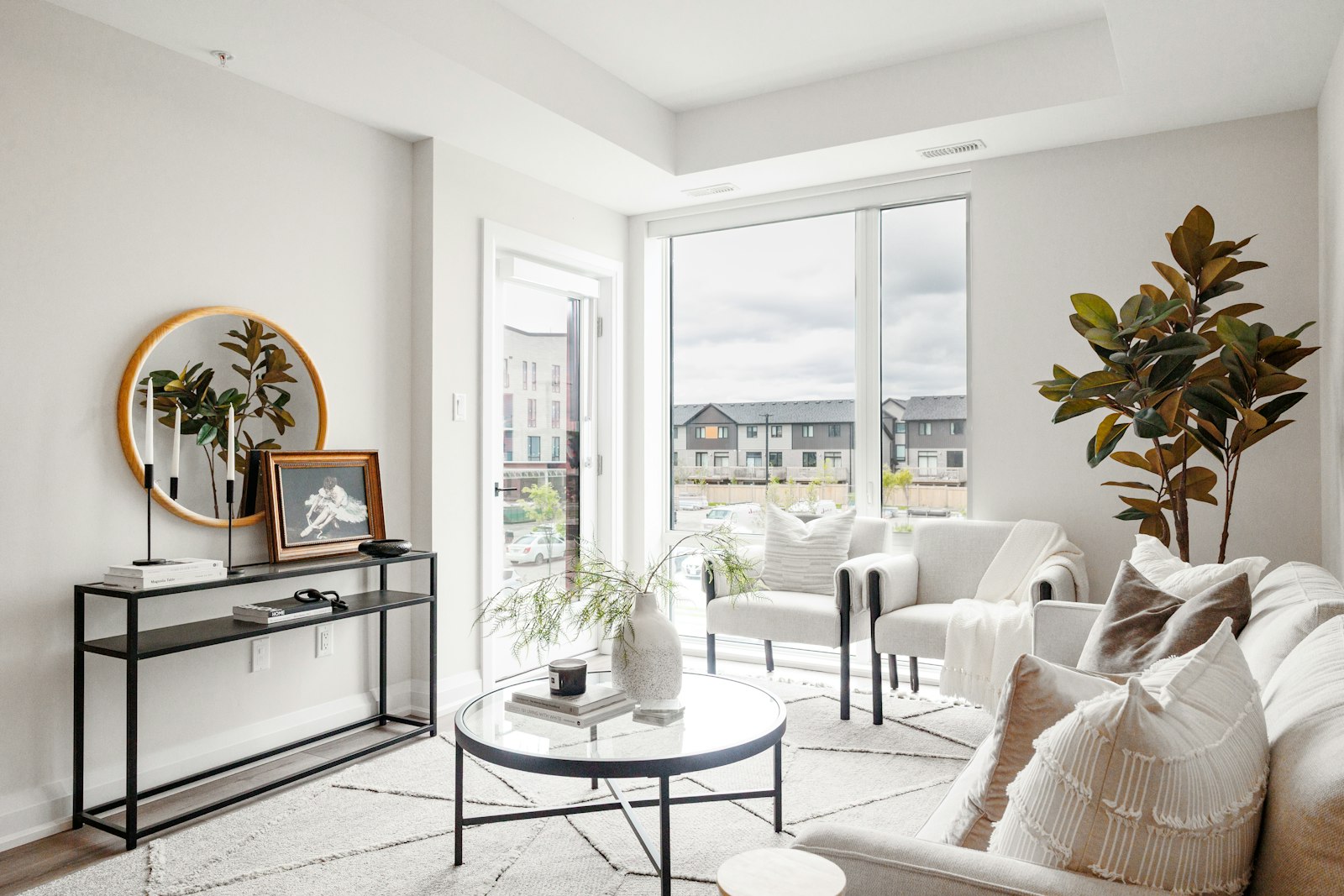 A bright neutral living room with a sofa, console table and round mirror