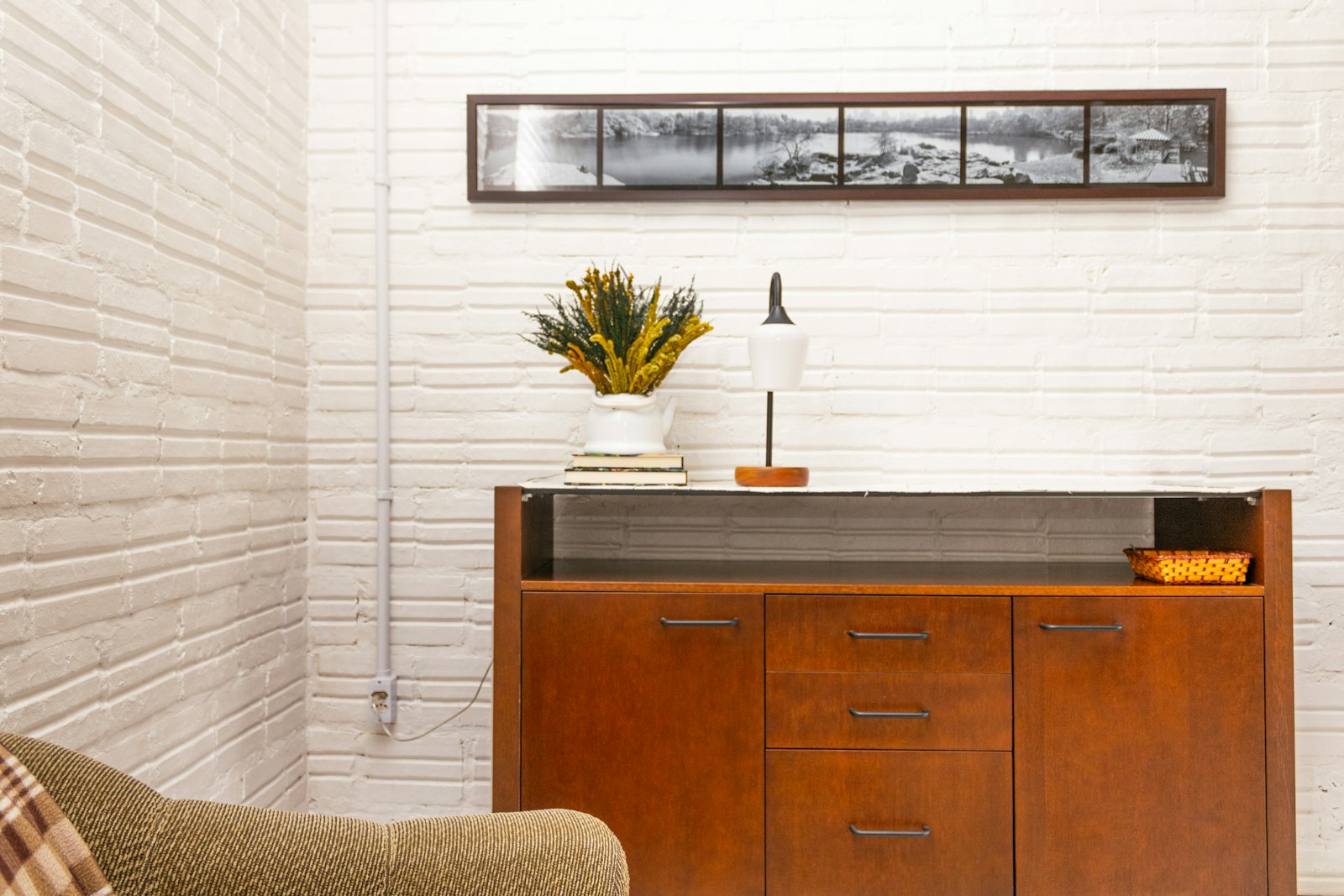 Mid-century wooden sideboard against a white brick wall in a living room
