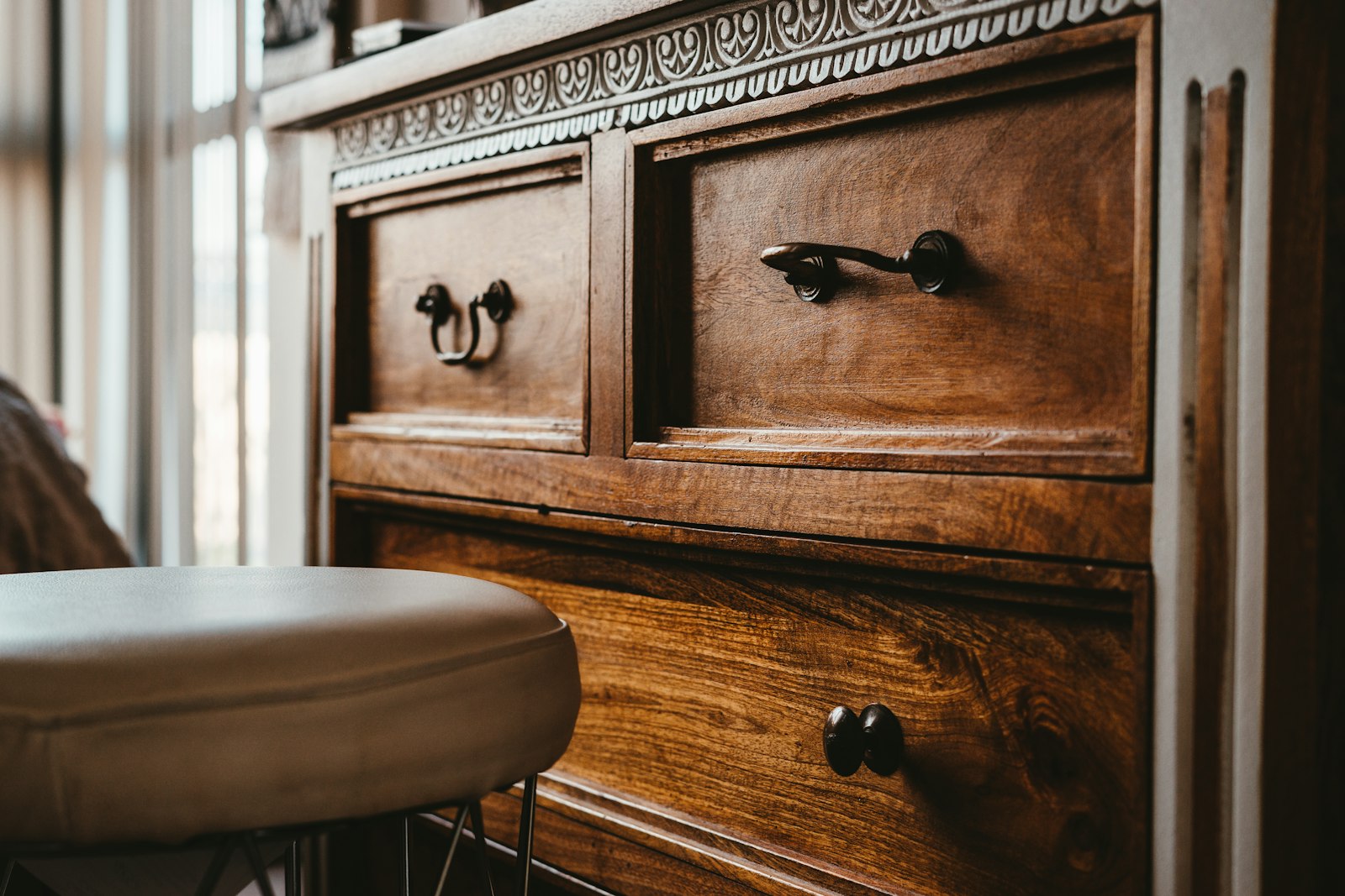 Close-up of a wooden chest of drawers with dark metal handles