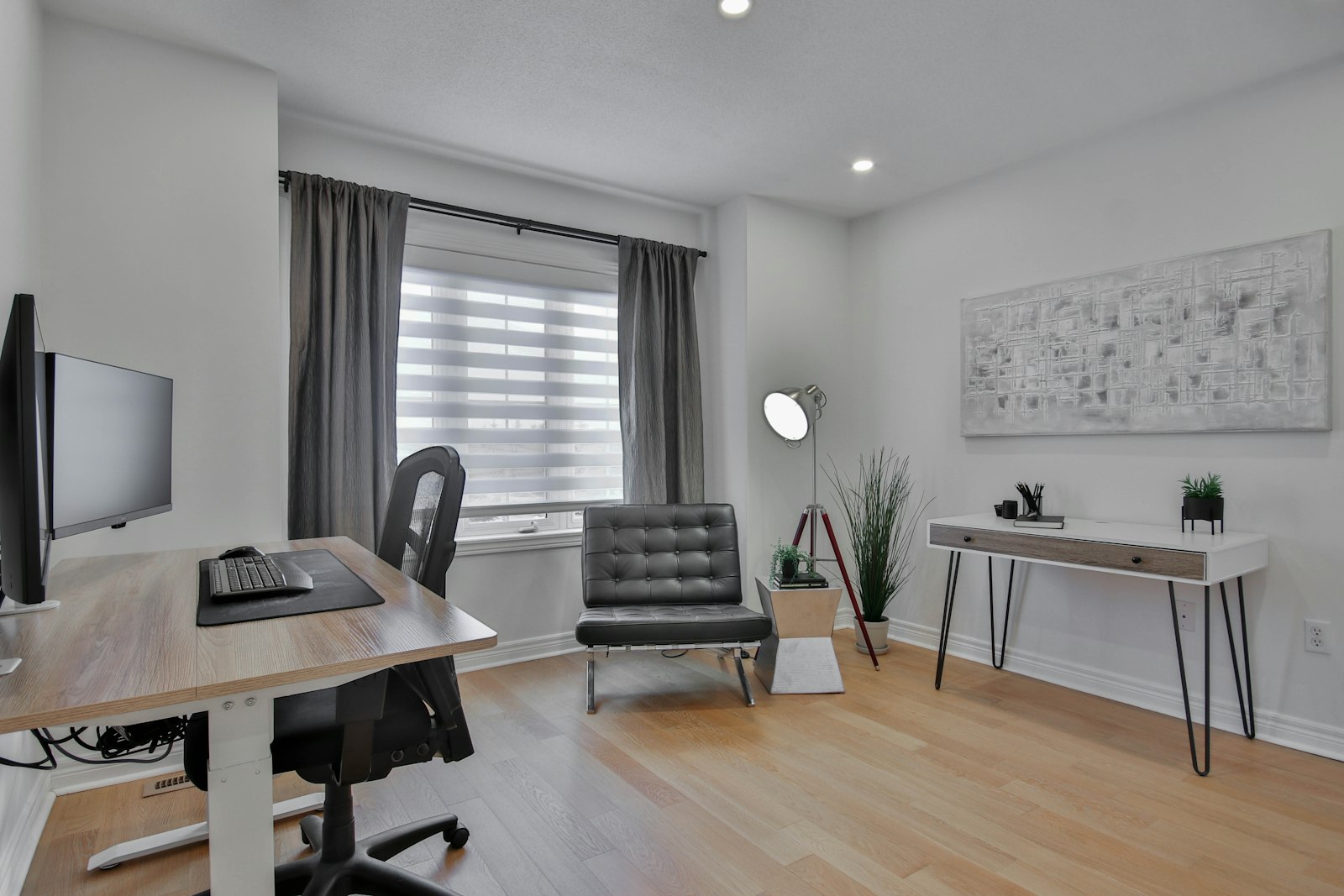 A bright, tidy home study room with a desk, monitor, office chair and a window with blinds letting in daylight