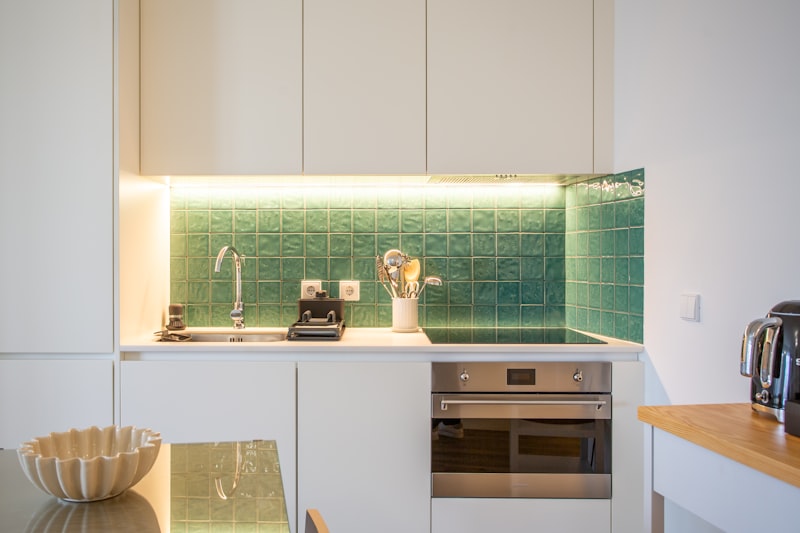A compact flat kitchen with a green tiled wet run beside a separate wooden dry worktop