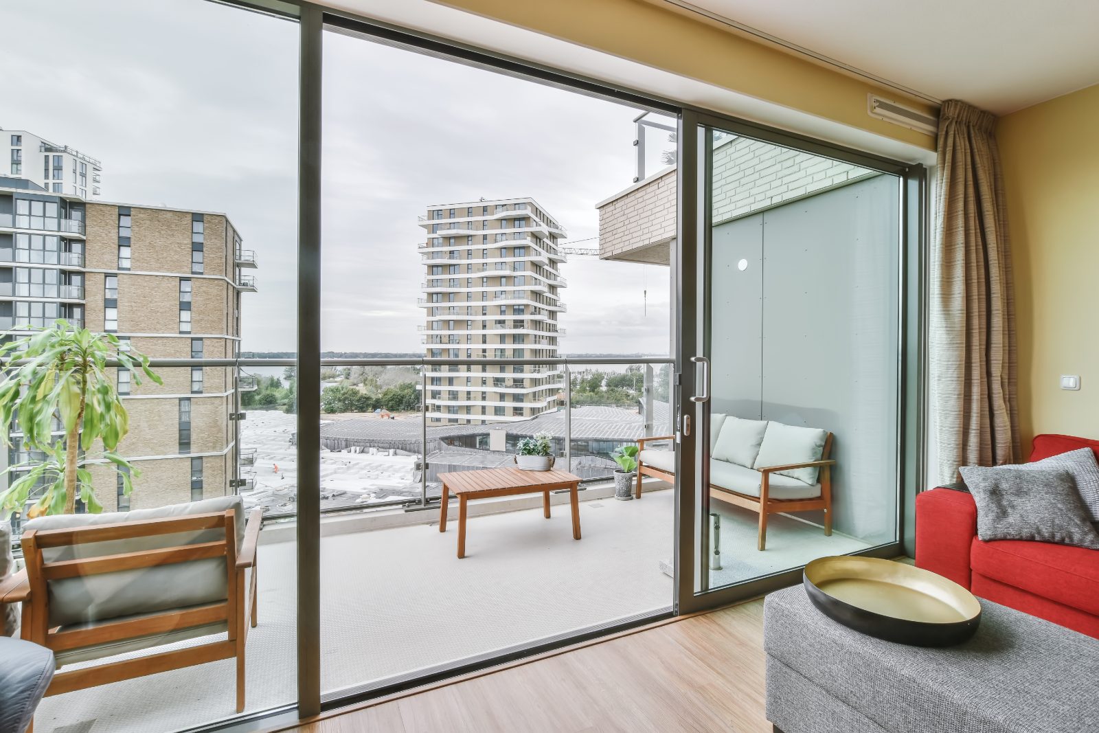 An open sliding glass door leading onto the balcony of a high-rise flat