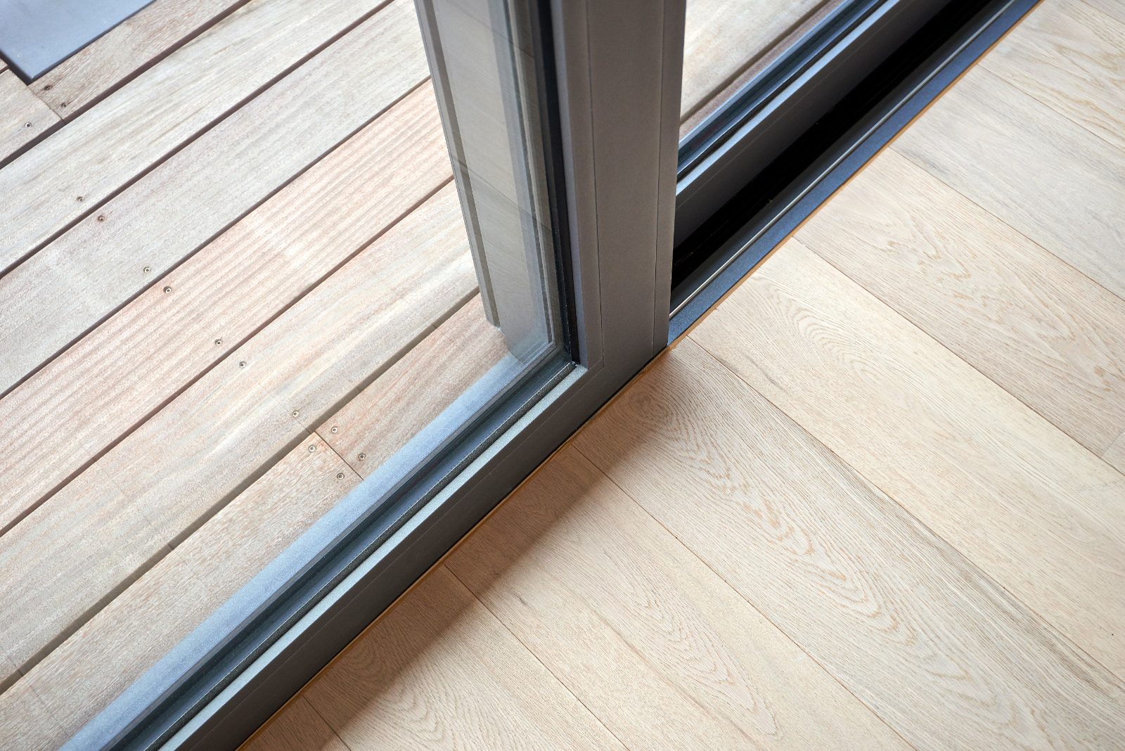Close-up of an aluminium sliding door track running across the floor beside a balcony