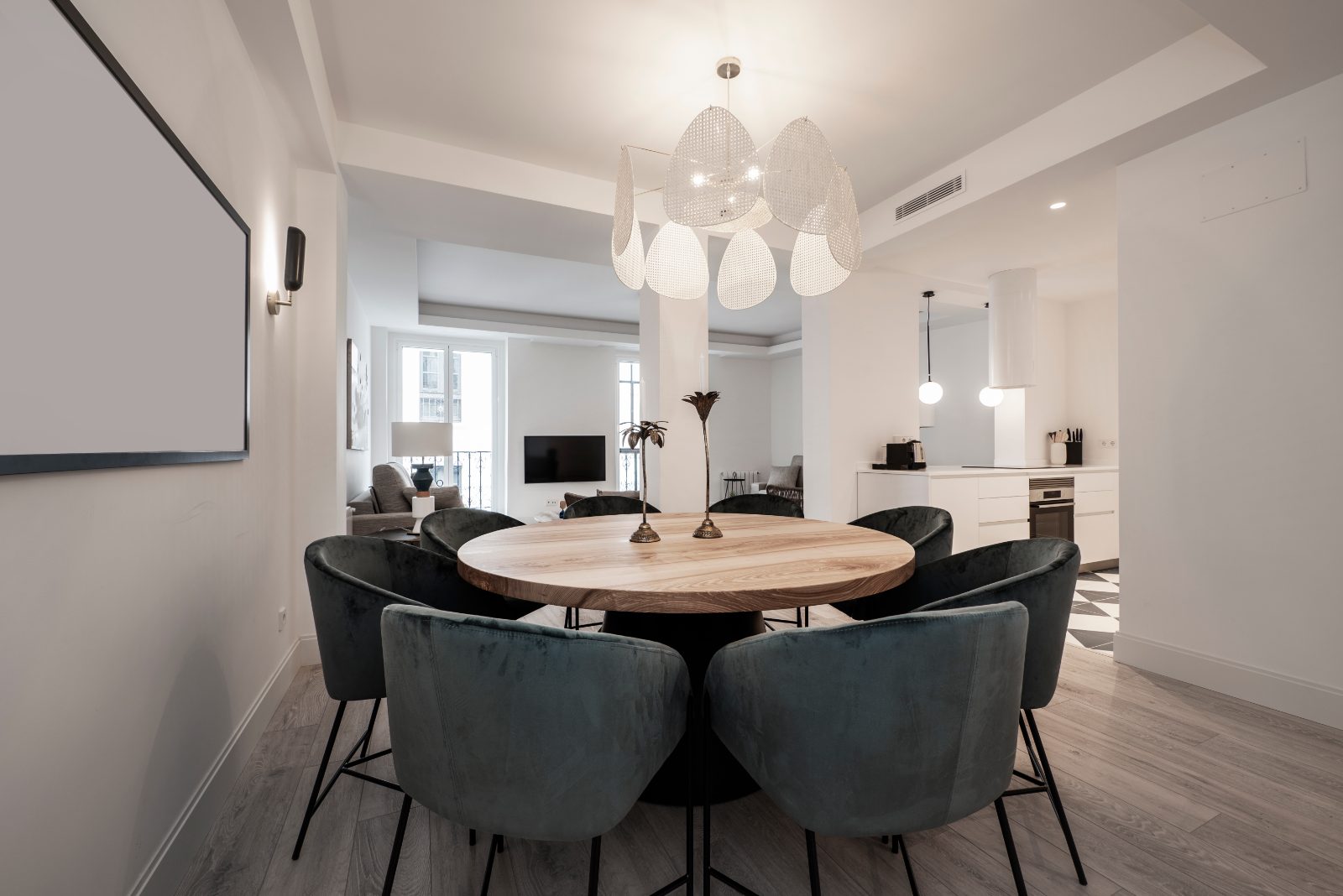 Round wooden dining table surrounded by fabric upholstered chairs in a modern apartment