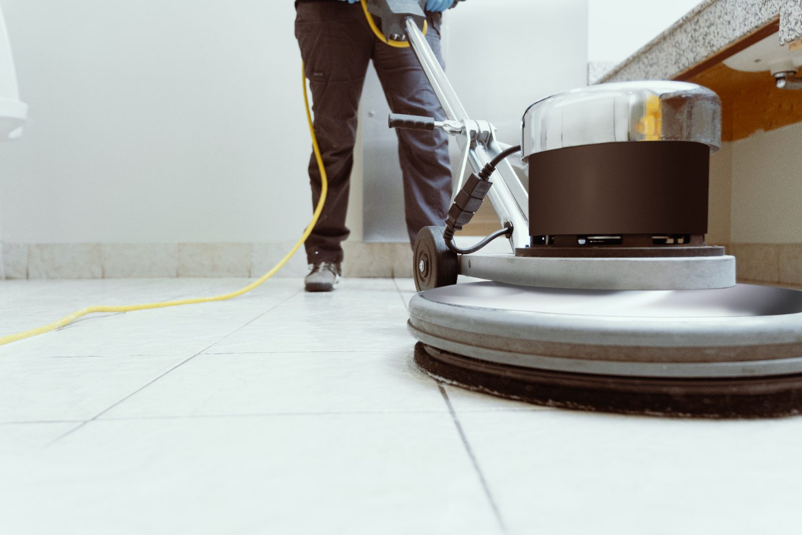A weighted rotary floor scrubbing machine working across a large tiled floor