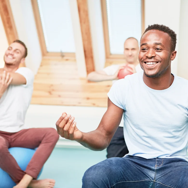A person of colour wearing a hijab with some books and a bag smiling optimistically