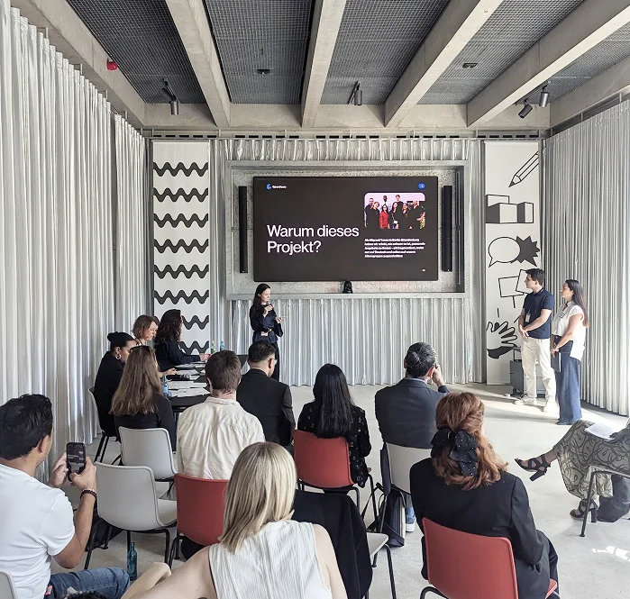 Three Leader presenting their project findings to an audience in a nice modern event space