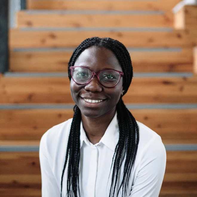 NextGen Leader Nimi sitting on wooden stairs smiling