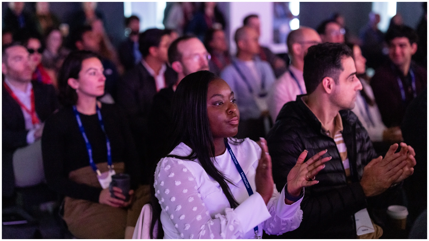 Group of people seated in an audience, attentively watching and clapping during an event or presentation.