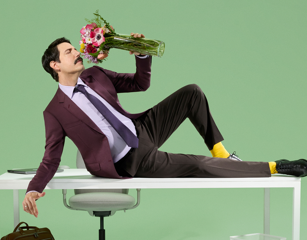 man lying on a table smelling flowers in a vase