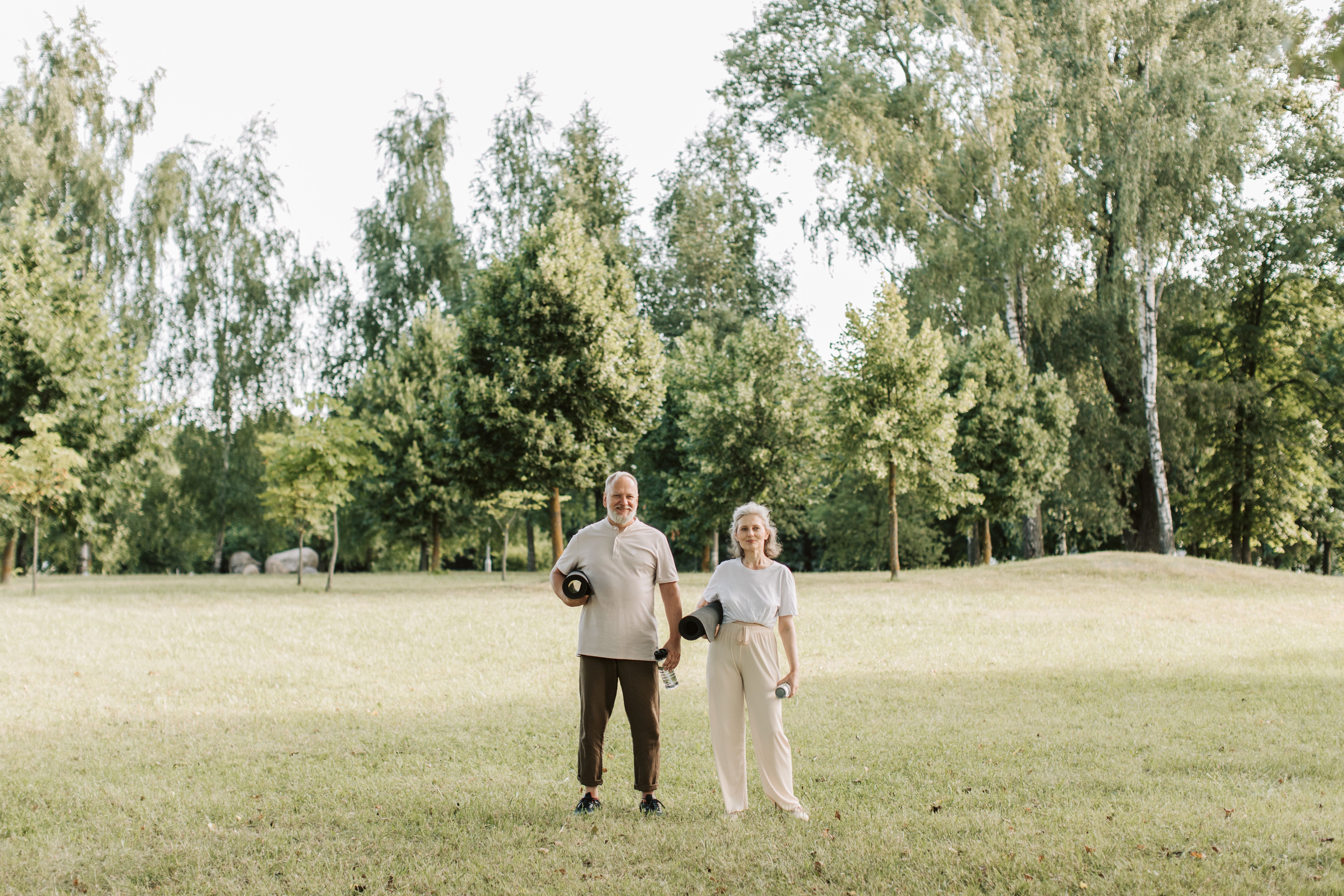 Twee mensen met yogamatten in een park