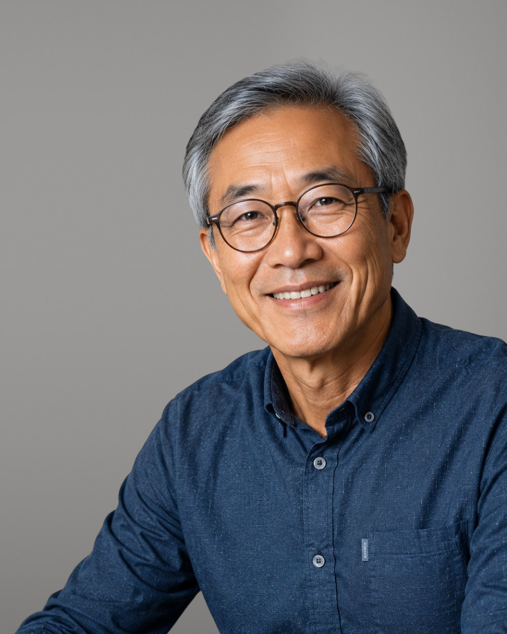 Senior professional with glasses in a denim shirt, smiling