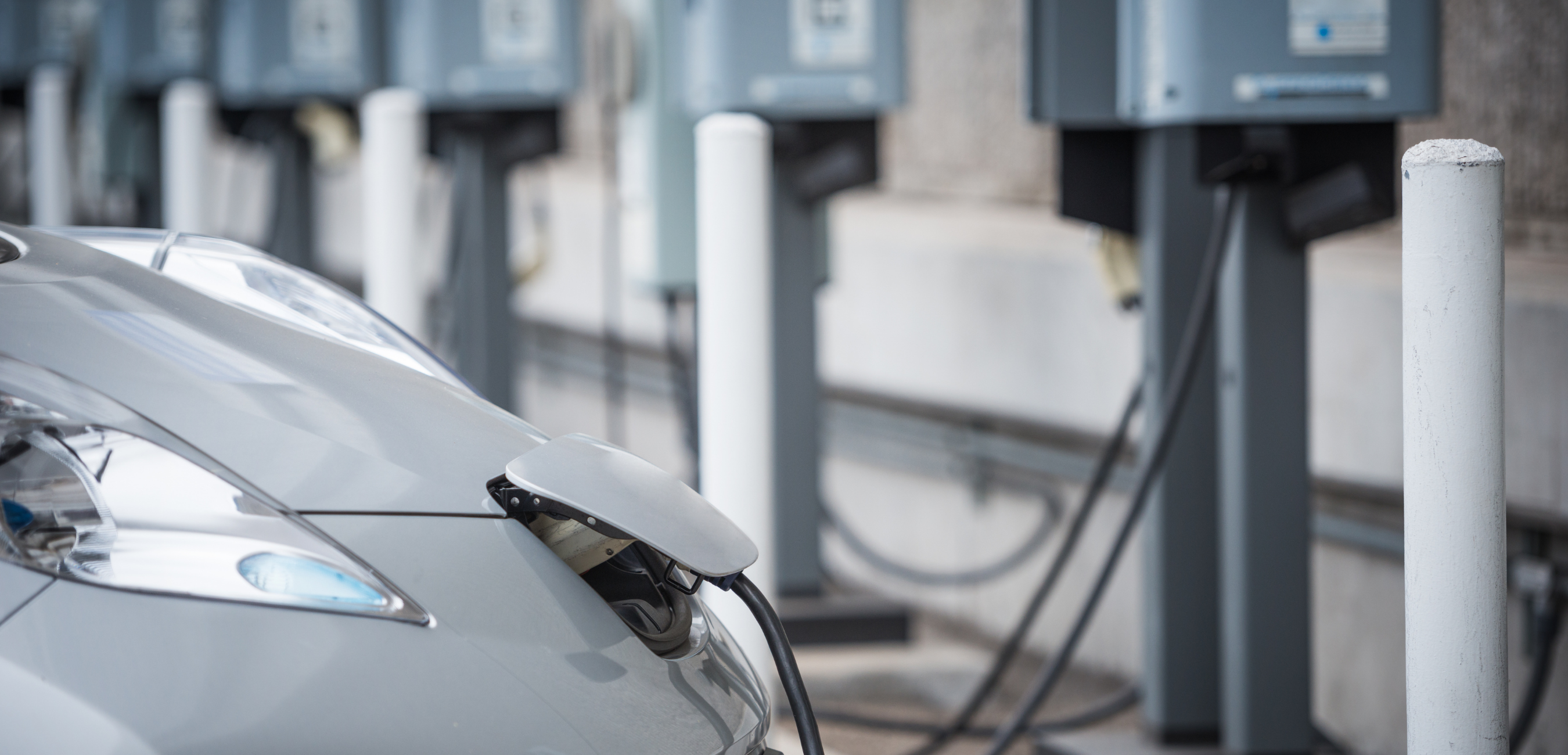 A parked plug-in electric car being charged at a public EV charging station.