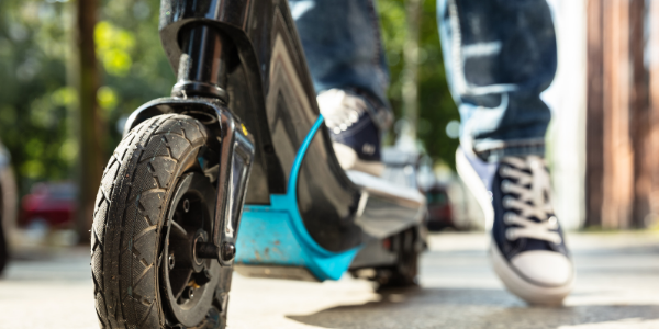 A person riding a black and blue electric scooter.