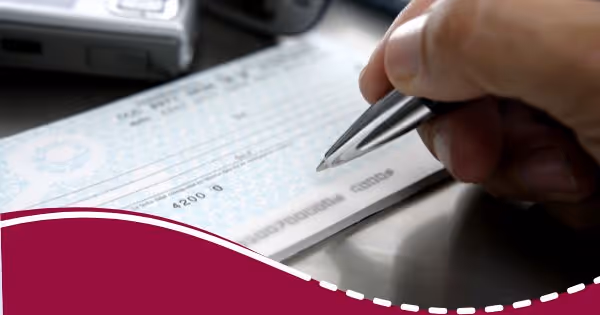 A person holding a pen and writing on a piece of paper