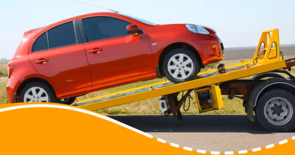 A red car is being towed by a tow truck