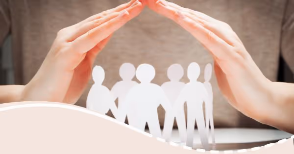 A person holding their hands over a paper cutout of a group of people