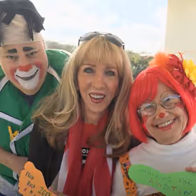Three people in costume and makeup smiling together at an event