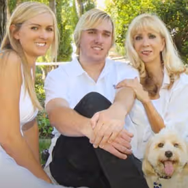 Family portrait with three people and a golden retriever in white clothing