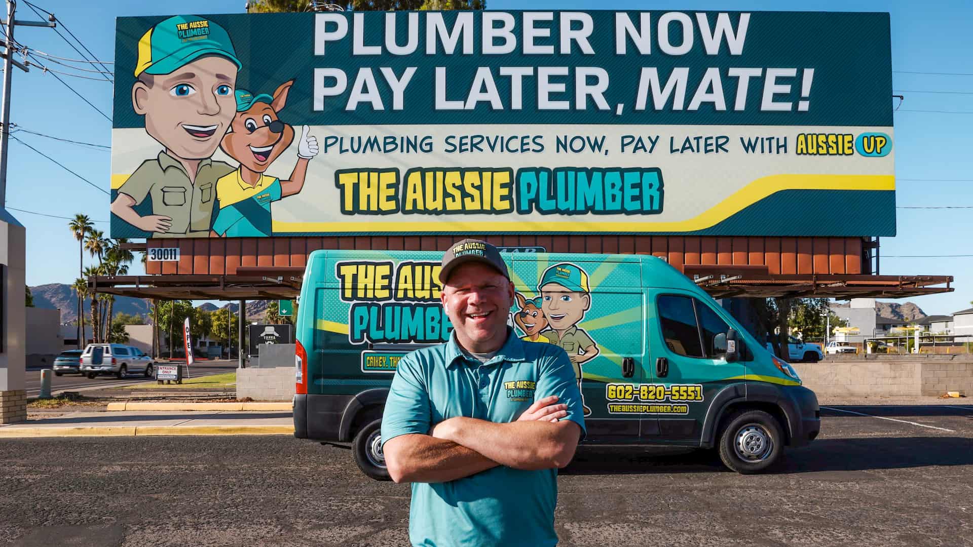 James Hill owner of The Aussie Plumber in Phoenix Arizona in front of AUSSIE UP billboard in Paradise Valley.