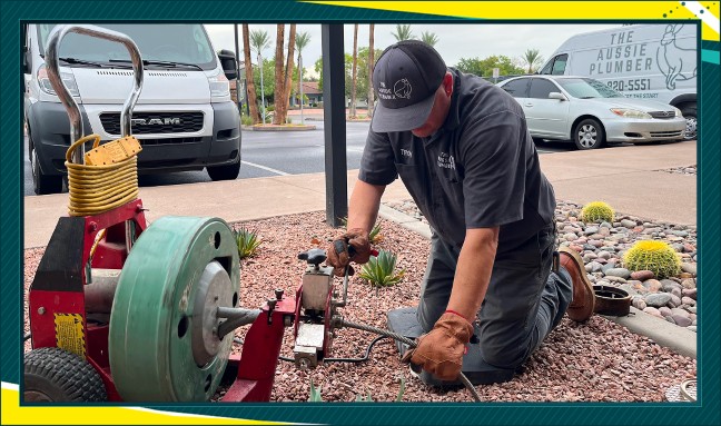 A service plumber for The Aussie Plumber kneels down to begin a sewer service for a property in Phoenix, Arizona