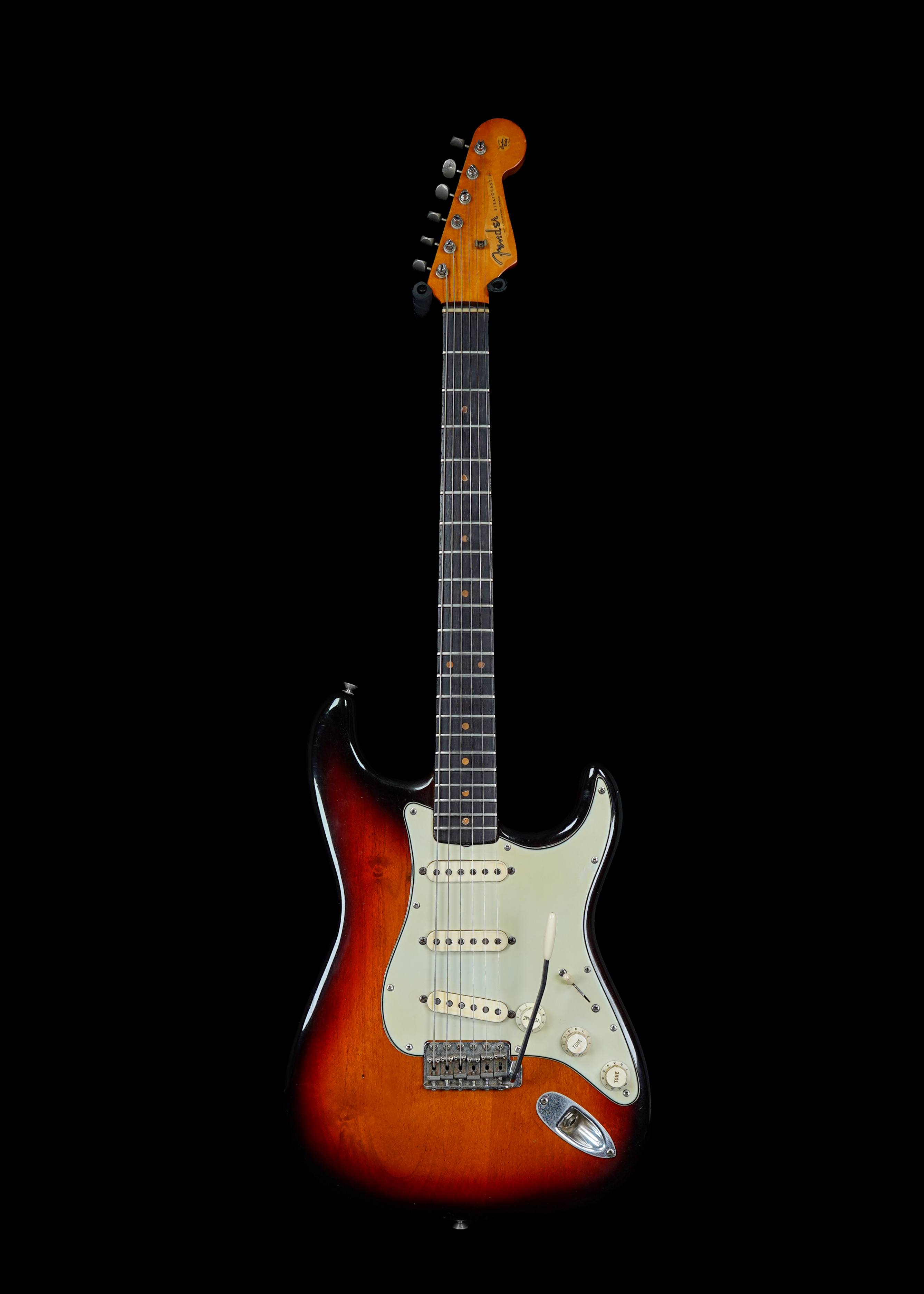 a professional photo of a 1960 Fender Stratocaster Sunburst vintage guitar by Tone Brothers, the vintage guitar shop to sell my vintage guitar