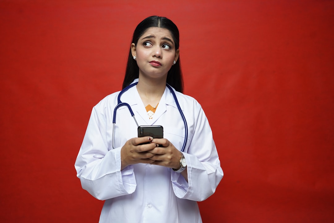A doctor holding a smartphone to message a patient in a clinic — Photo by Fotos on Unsplash