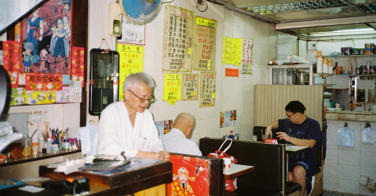 Customers inside a Hong Kong cha chaan teng, one messaging on his phone - WhatsApp auto-replies keep small businesses responsive