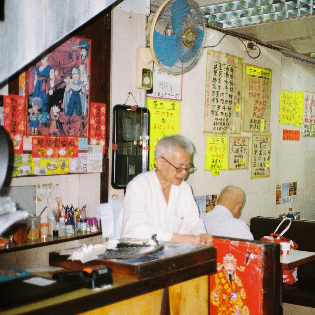 Hong Kong cha chaan teng owner at the counter - the kind of small business that relies on WhatsApp auto-replies
