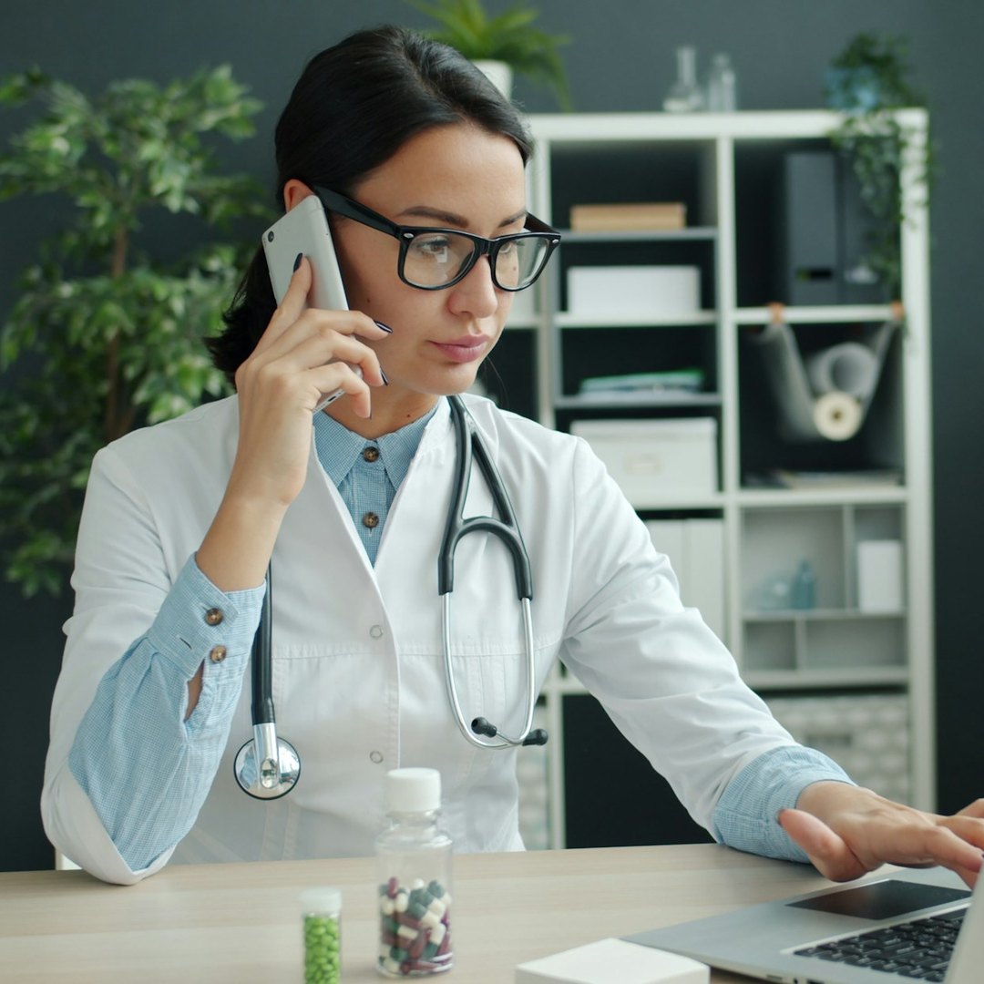 Clinic doctor confirming appointments on a smartphone at her desk