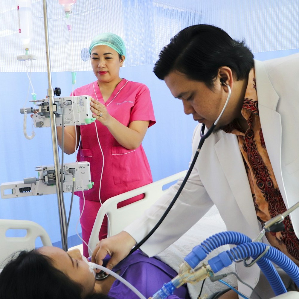 Clinician and nurse at a hospital bedside in Asia, illustrating post-discharge patient follow-up