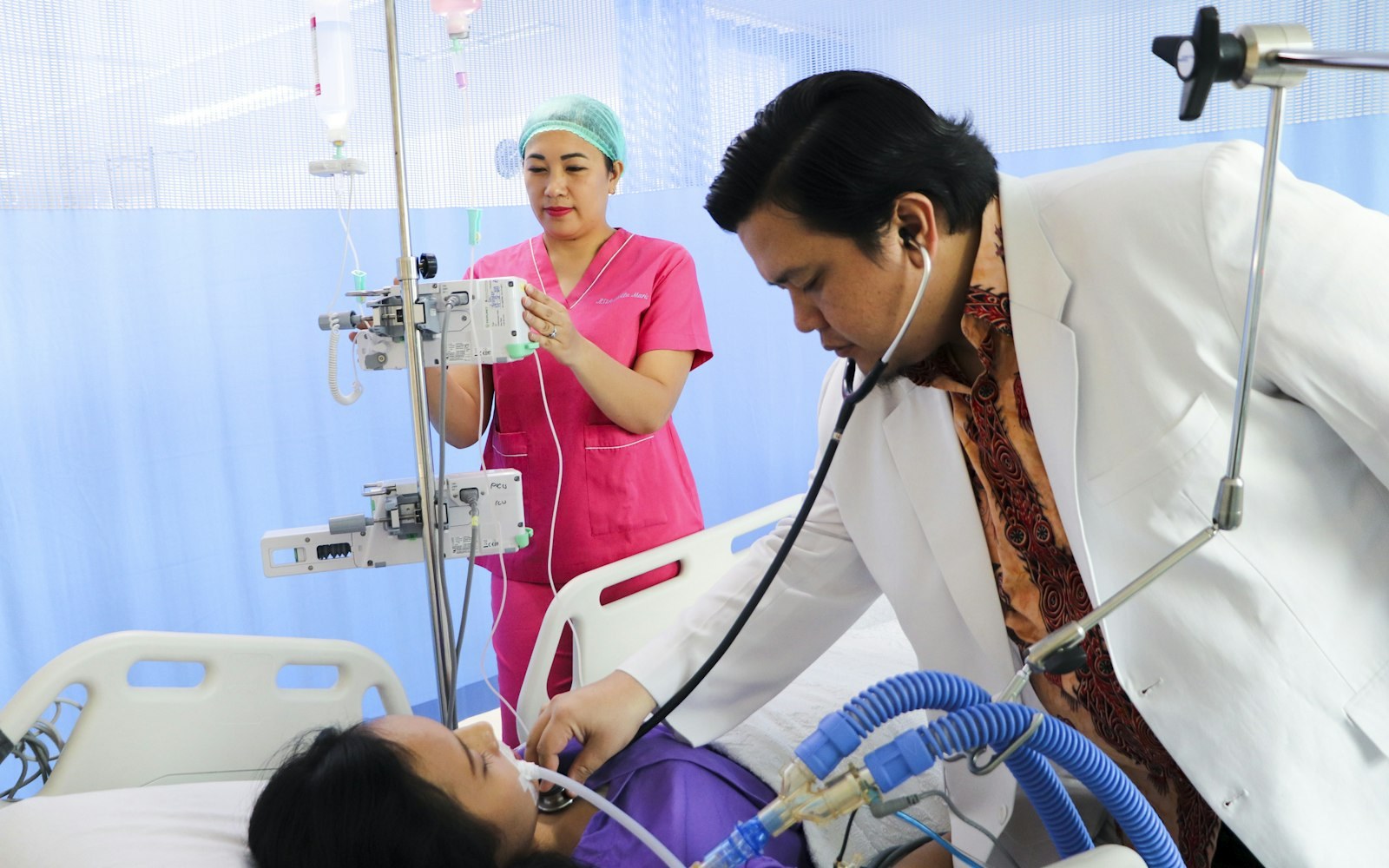 Clinician and nurse at a hospital bedside in Asia, illustrating post-discharge patient follow-up