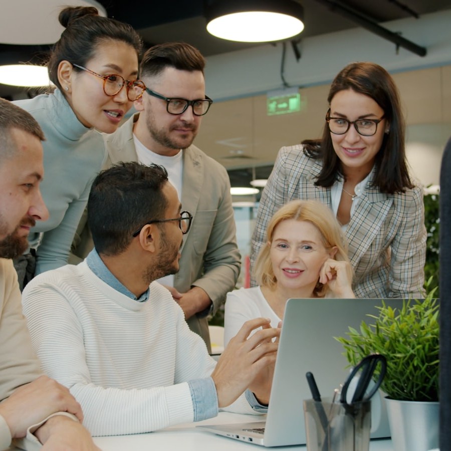 Diverse team collaborating around a laptop in office.