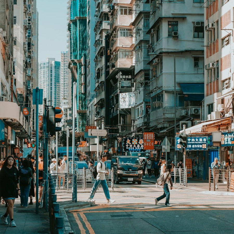 a group of people walking down a street next to tall buildings