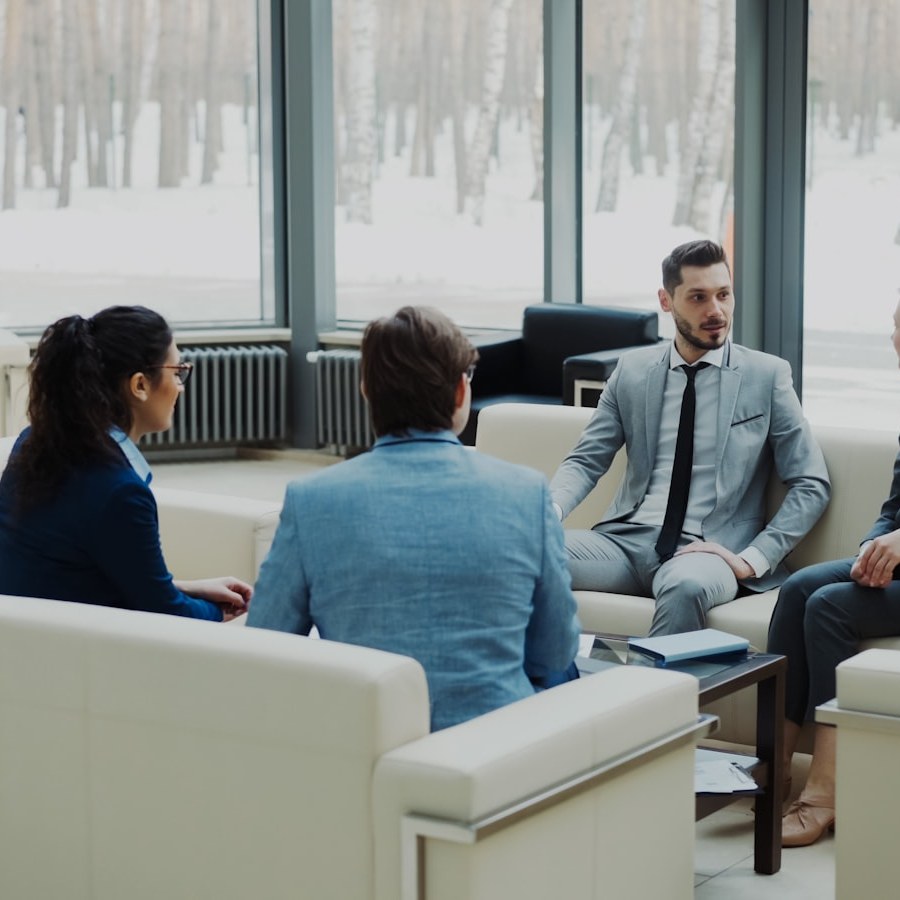 Four professionals in a modern office meeting space.