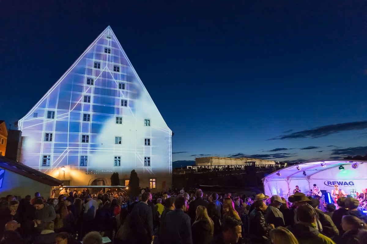 Illuminierte Hausfassade und Konzertbühne beim Regensburger Bürgerfest 2015.